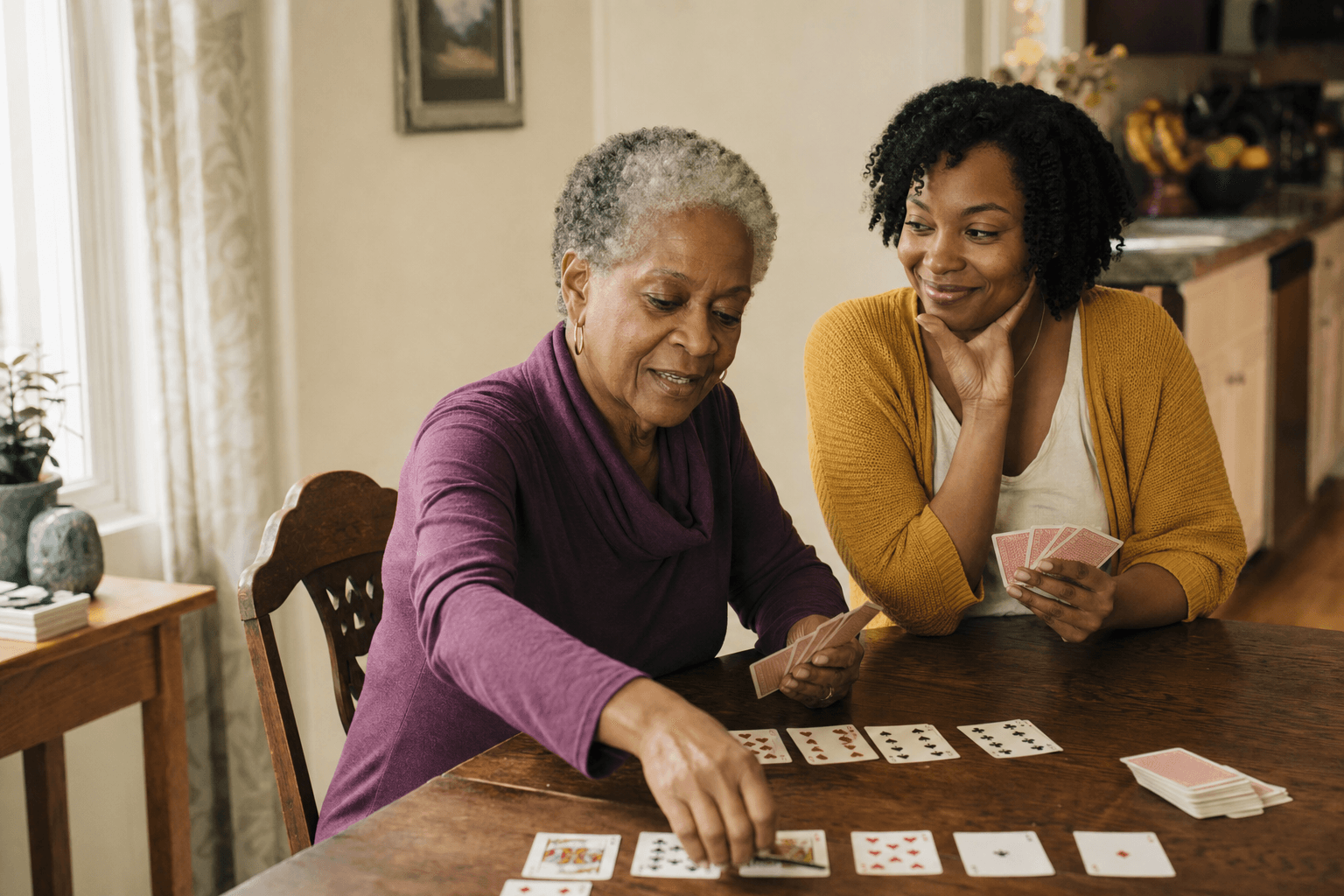 An older woman and her companion playing cards at the kitchen table